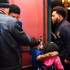 An usher greeting two children and an adult at the entrance to the theater.