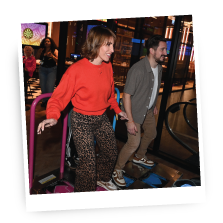 Two people dancing on a dance game at an arcade.