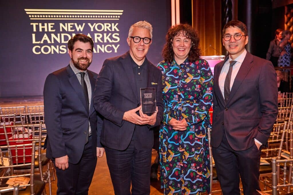 Four people posing with an award at The New York Landmarks Conservancy event in a warmly lit hall.