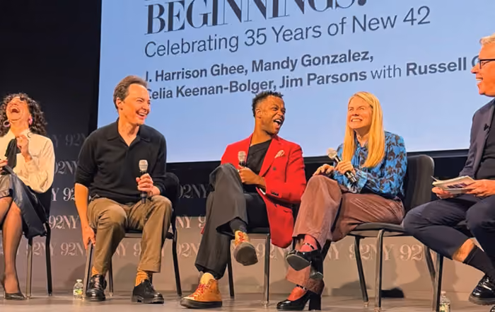 A group of 4 people sitting on stage in front of a screen 