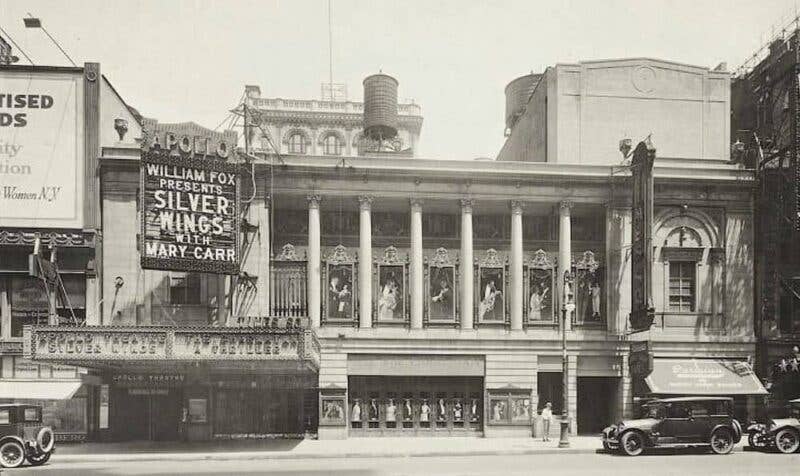 Times Square facade with marquee advertising Silver Wings and vintage cars parked on the street.
