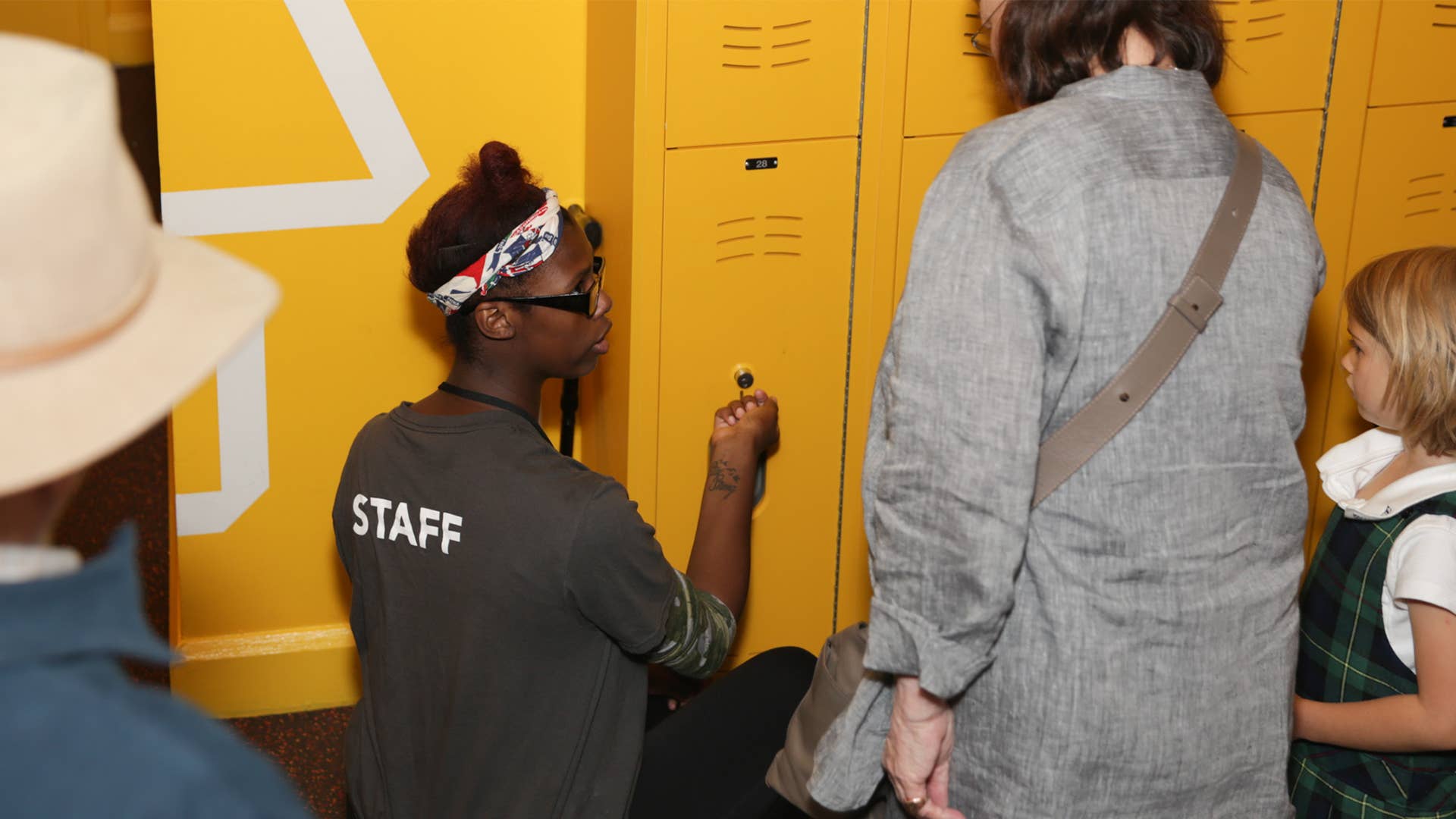A New Victory Usher opens a yellow locker for a patron.