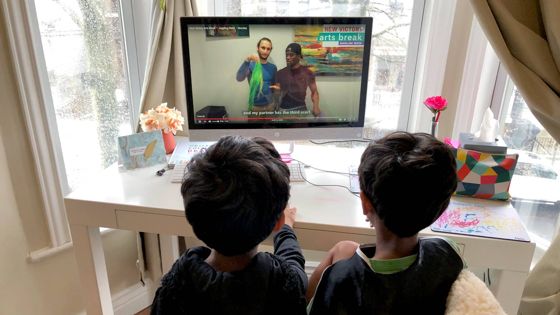 Two kids watch a video on a computer.