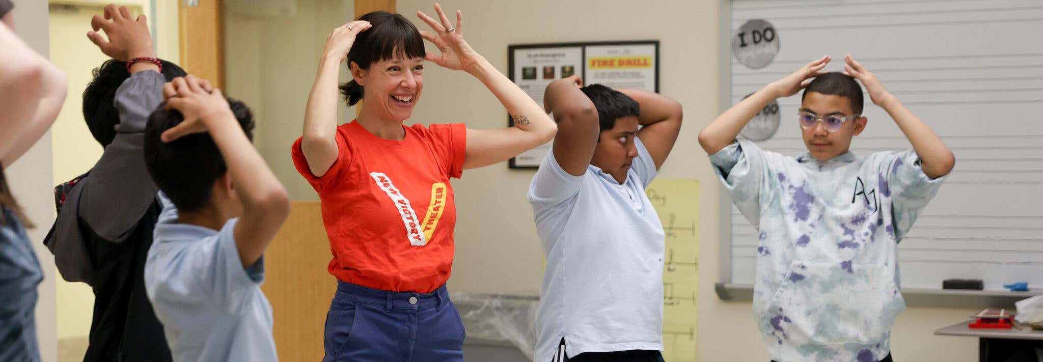 A woman and kids with hands one their heads.