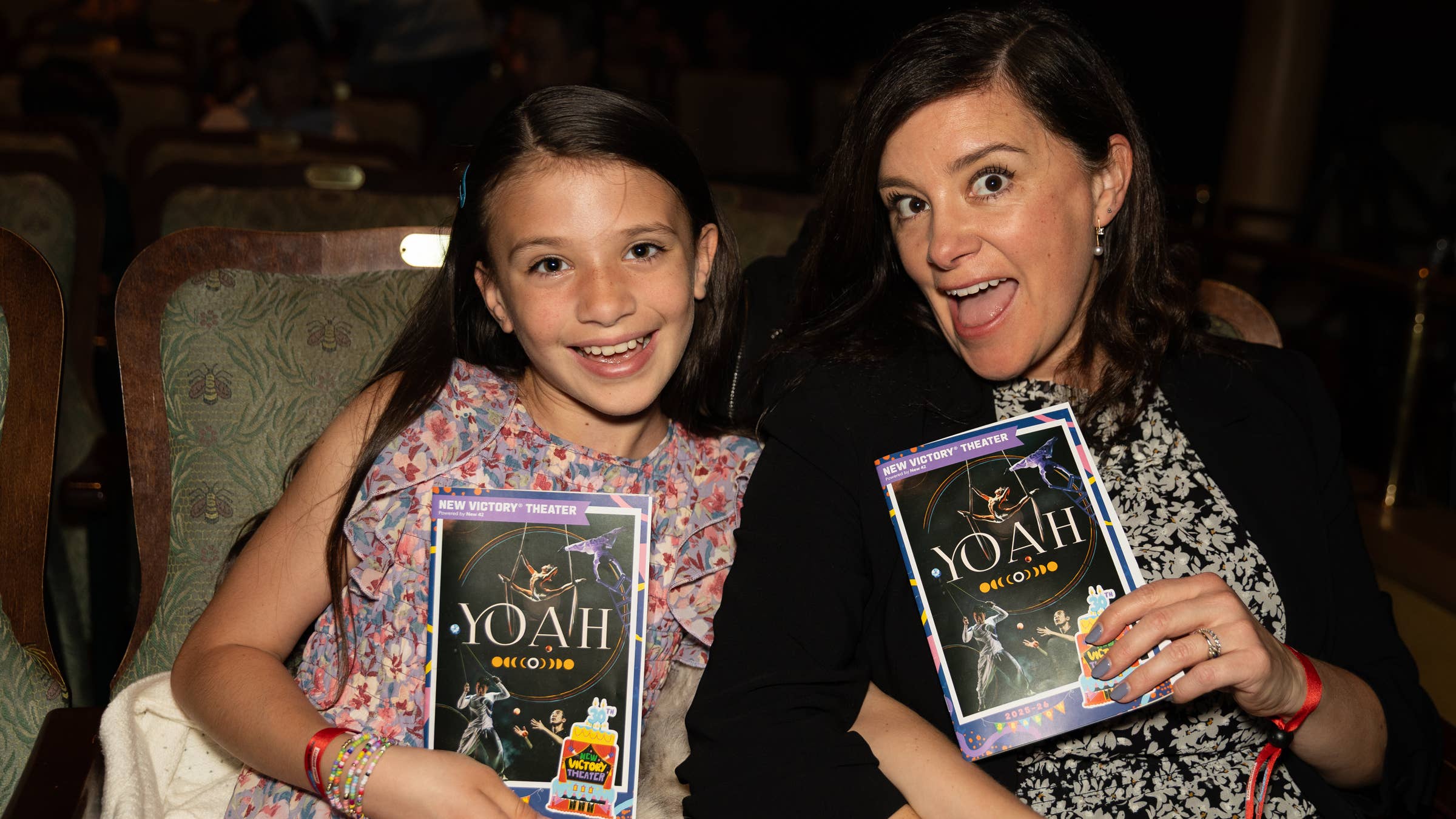 Smiling woman and girl holding New Victory Theater program book before a performance