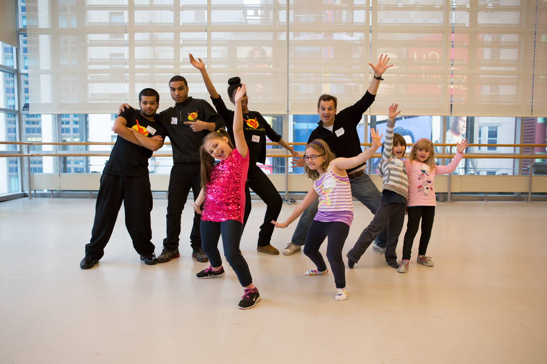 Four kids and four adults strike a pose with their arms in the air.