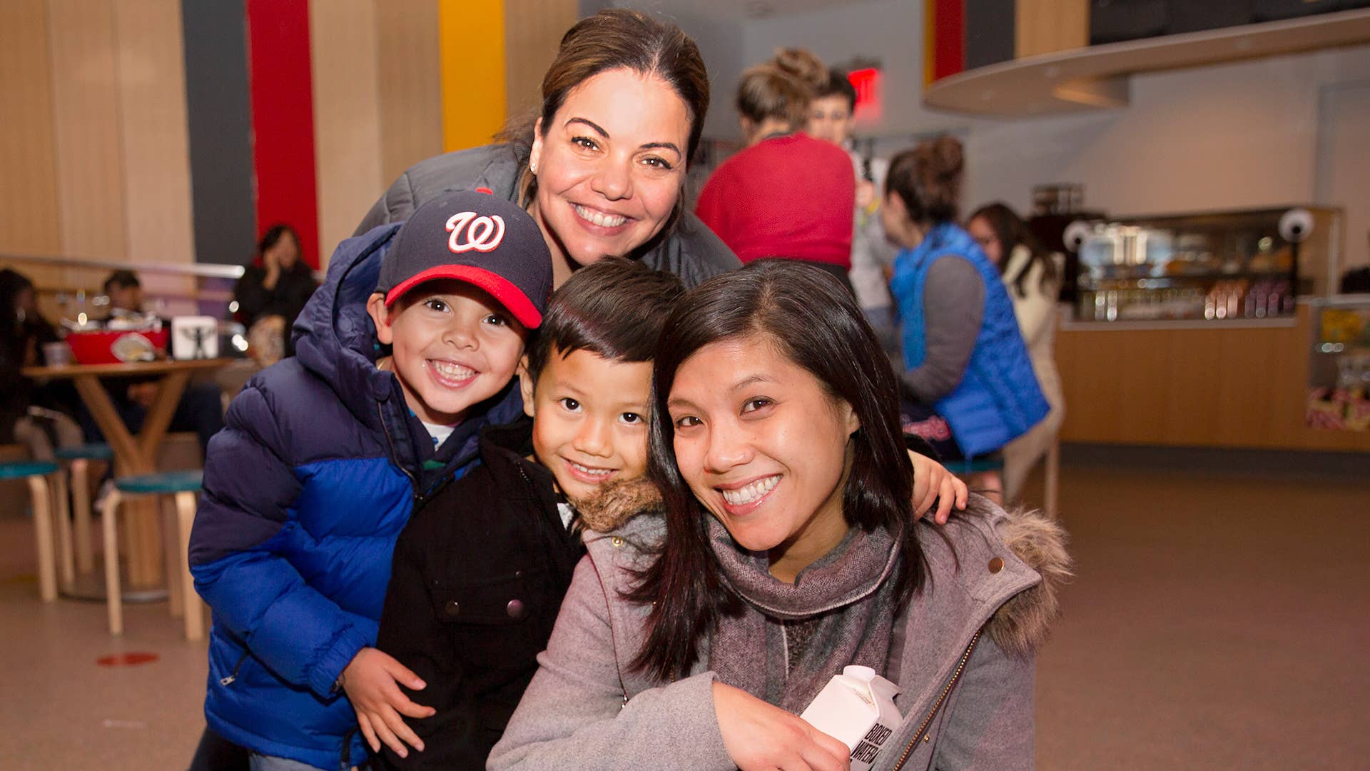 Two women and two kids huddled together smiling.