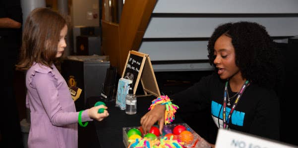Usher helps young patron select a fidget at accessibility table