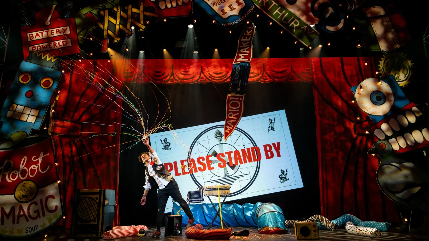 A man releases a colorful confetti popper over his head in front of a screen that reads 