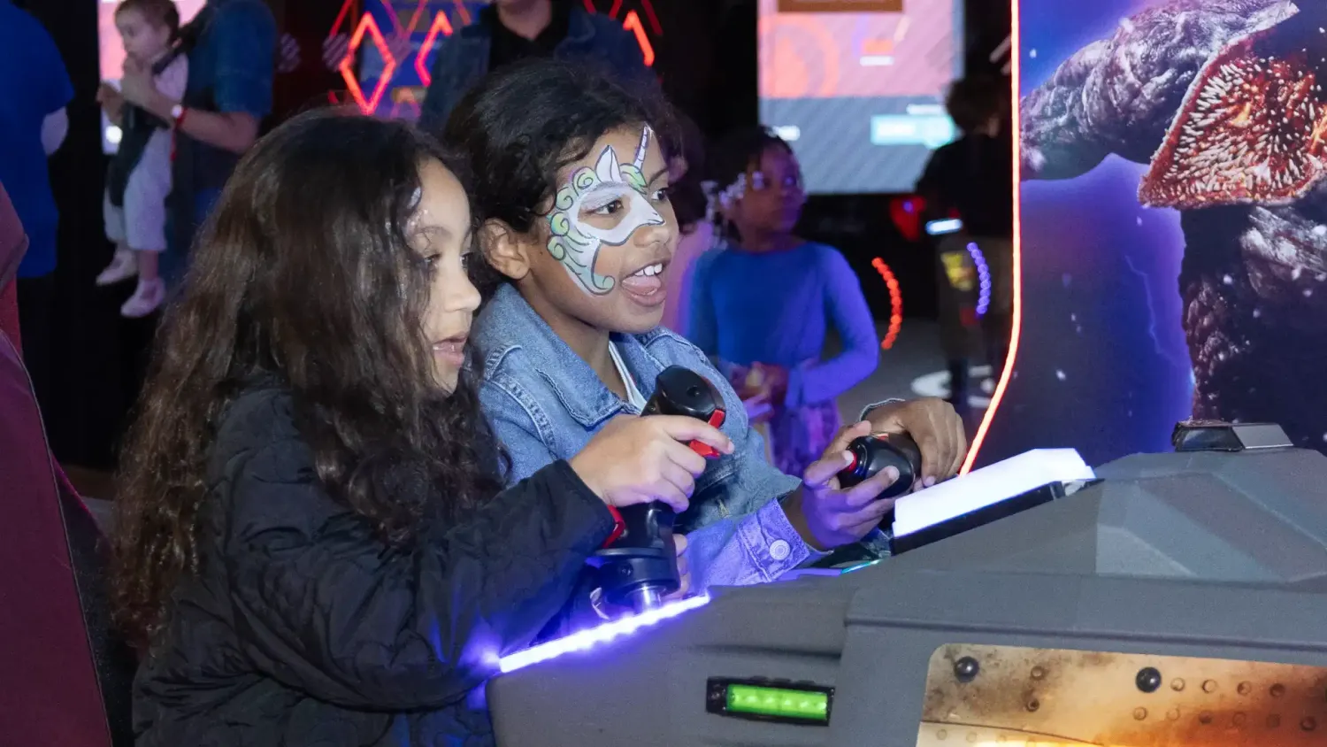Two kids, one with face paint, play a joystick game at Dave & Buster's.