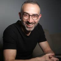 Smiling man in a black shirt with a dark grey background