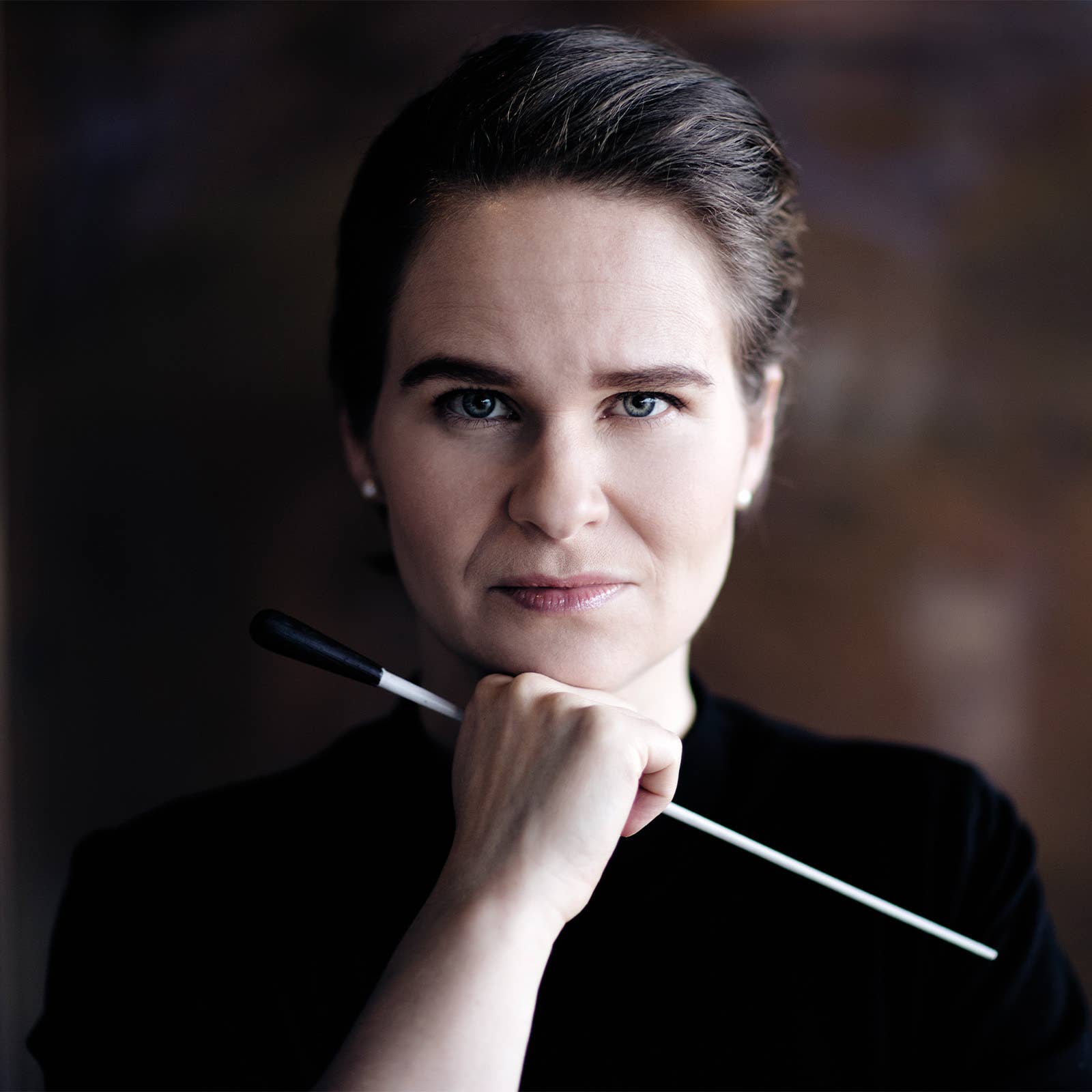 Close-up portrait of a woman with short hair holding a baton, looking at the camera.