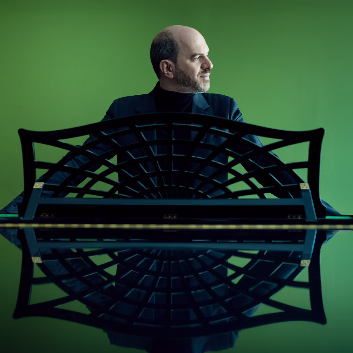 male musician standing behind an ornate piano on a green background