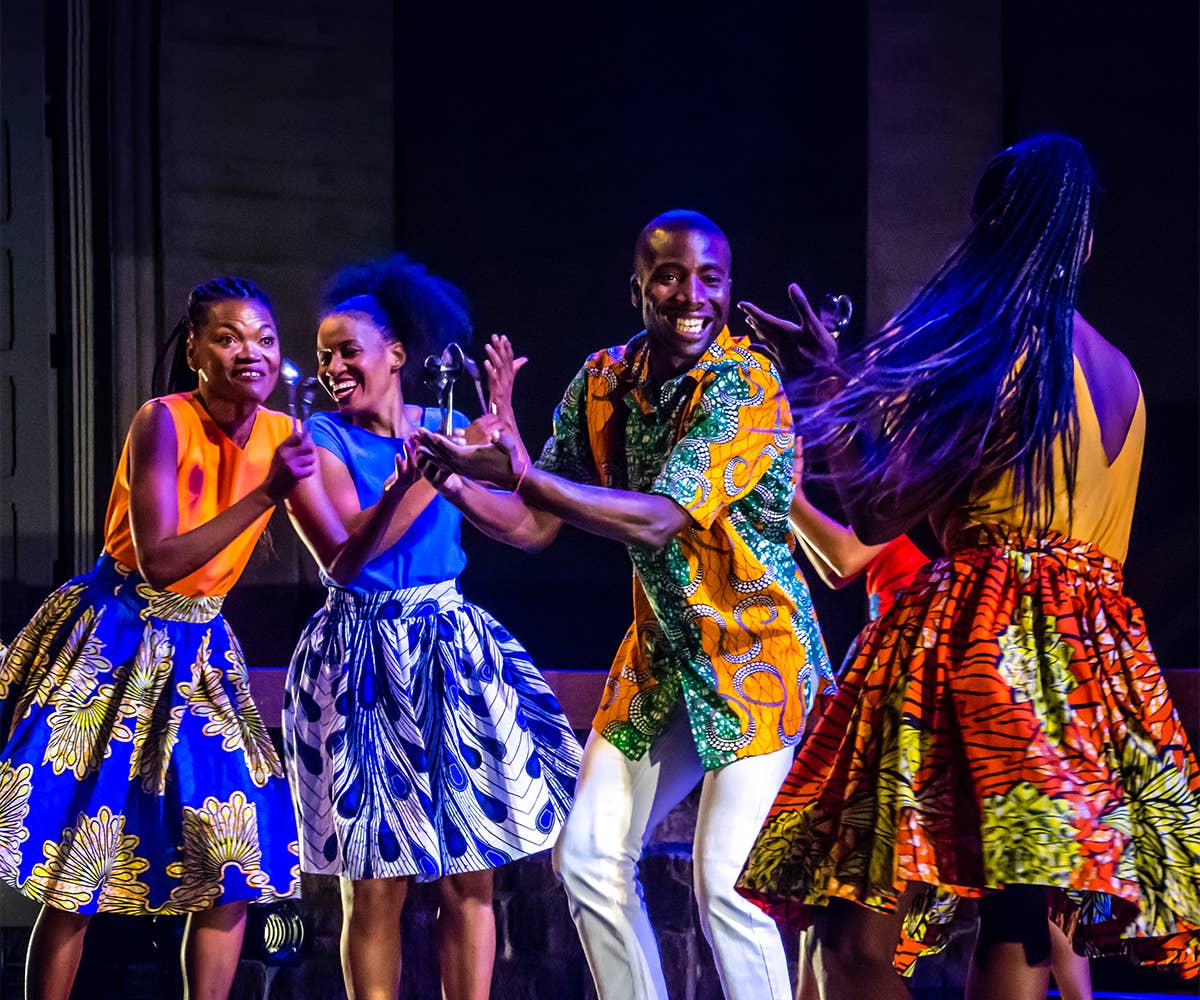 A group of dancers from Viver Brasil gathered in a circle are clapping. 