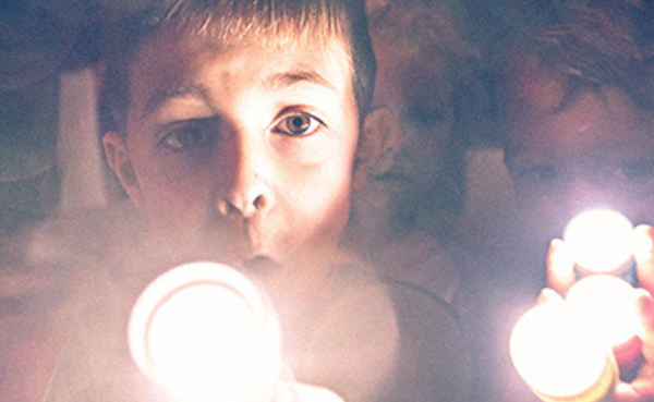Two kids with flashlights at a performance of FORTS
